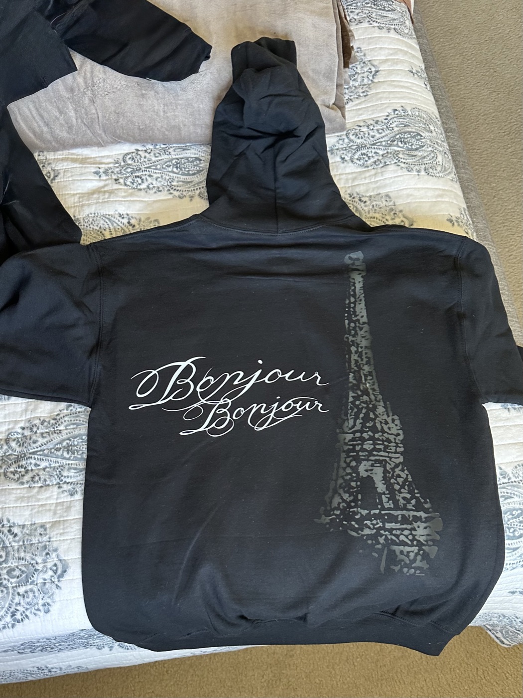 Black hoodie with Bonjour Bonjour script and an Eiffel Tower print