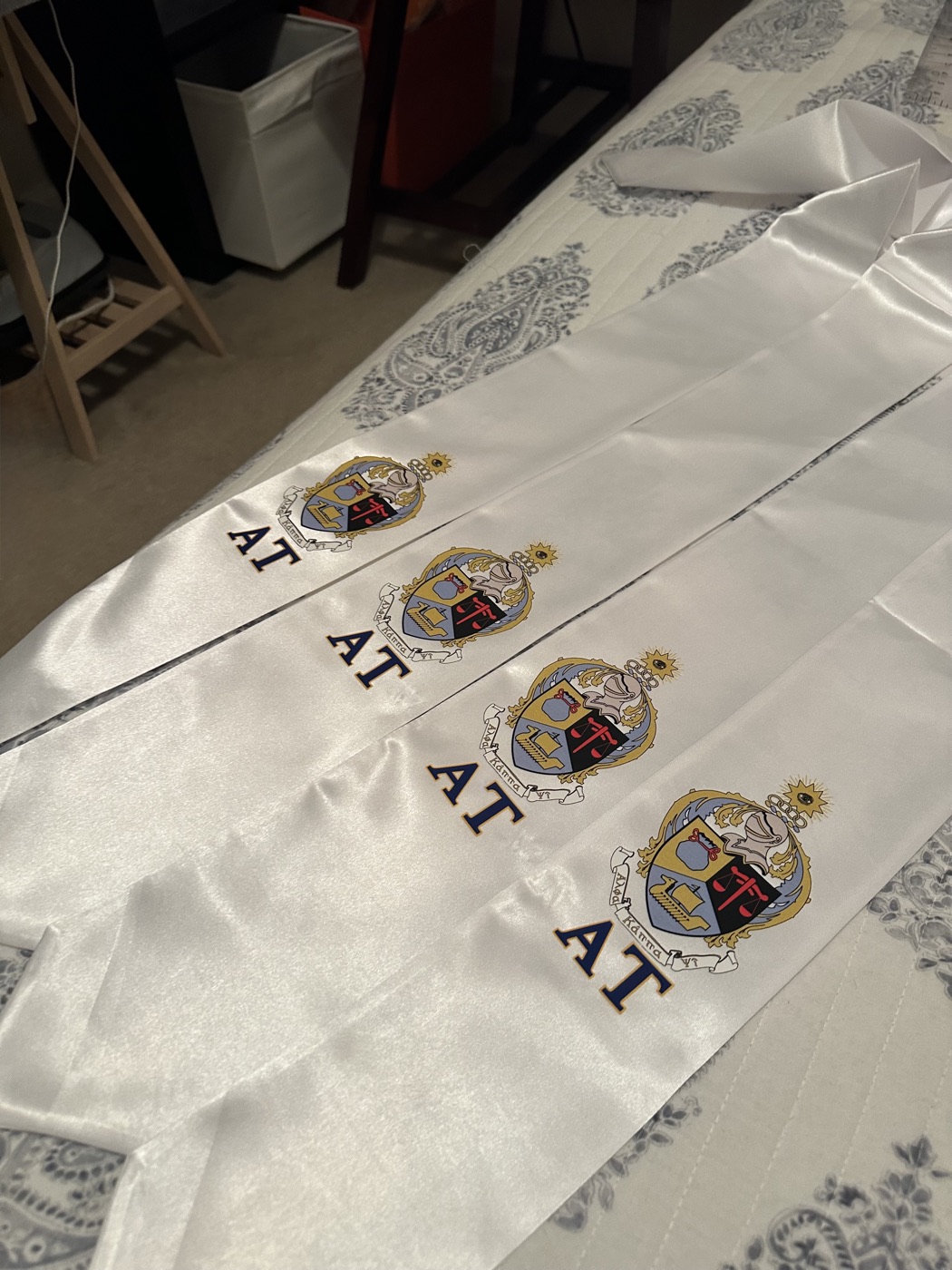 White satin sashes printed with the Alpha Tau crest and letters